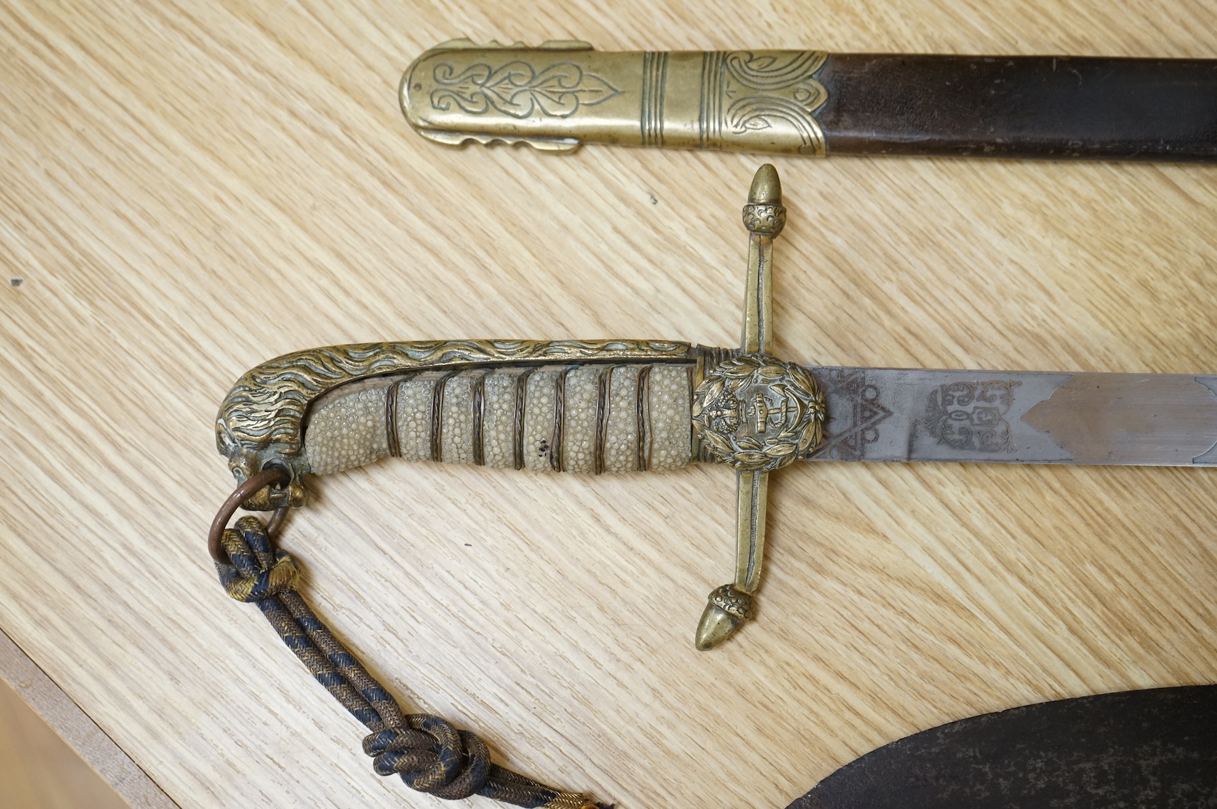 A post 1902 Naval Officer’s Dirk, the regulation blade with crowned fouled anchor, regulation hilt with remains of bullion dress knot in its leather scabbard with brass mounts, locket engraved with owners initials; RSA